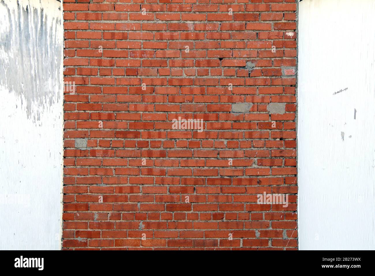 a faded white wood and old red brick garden shed exterior wall Stock Photo