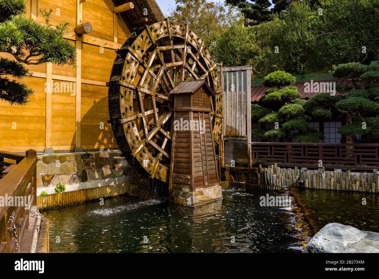 Hong Kong - January 18 2020 : Chinese Cottage with Ancient Waterwheel at Nan Lian Garden, Diamond Hill, Kowloon, Medium Shot, Eye Level View Stock Photo