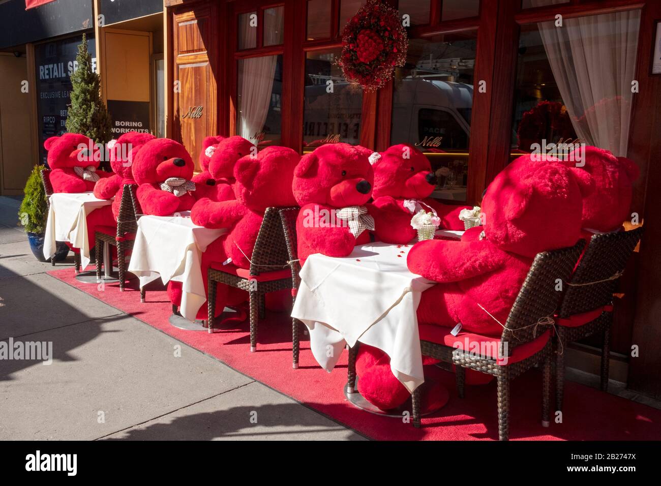 For Valentine's Day, 12 giant red stuffed bears sit at outside tables at Nello's for afternoon tea. On Madison avenue on the East Side of Manhattan, Stock Photo