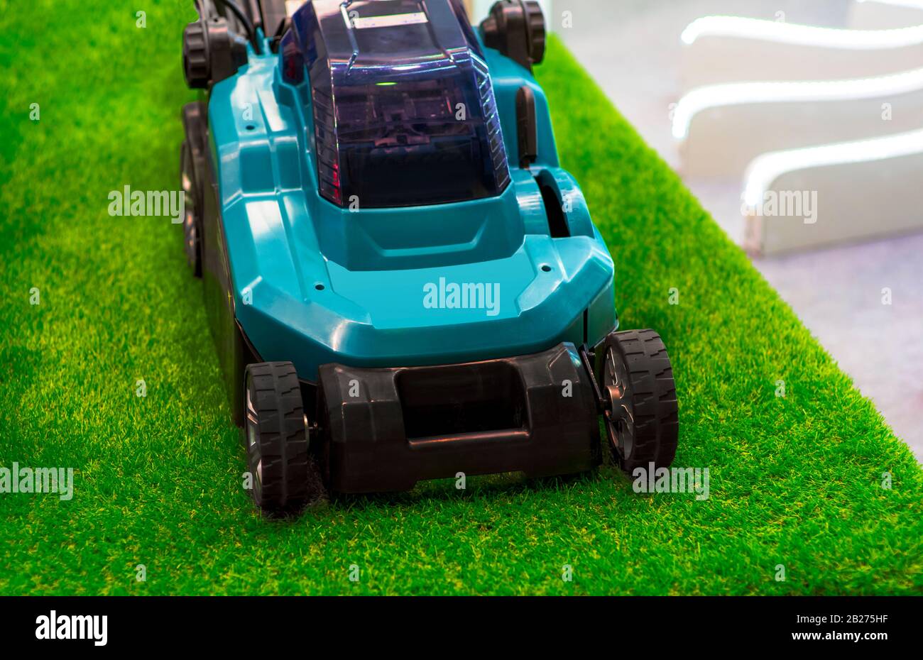 Turquoise lawn mower on grass. Stock Photo