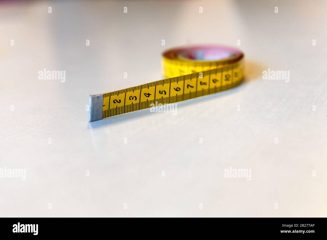 yellow tape measure on a white background Stock Photo - Alamy