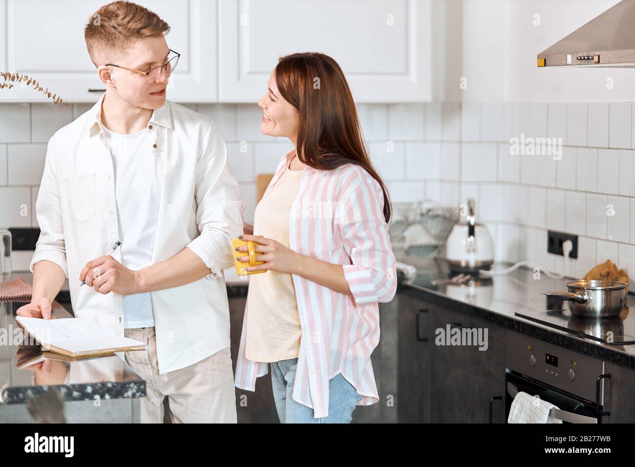 clever man listening to his wife advice, inspiration, handsome man in eyeglasses holding a pen and discussing his future book with wife, writer asking Stock Photo