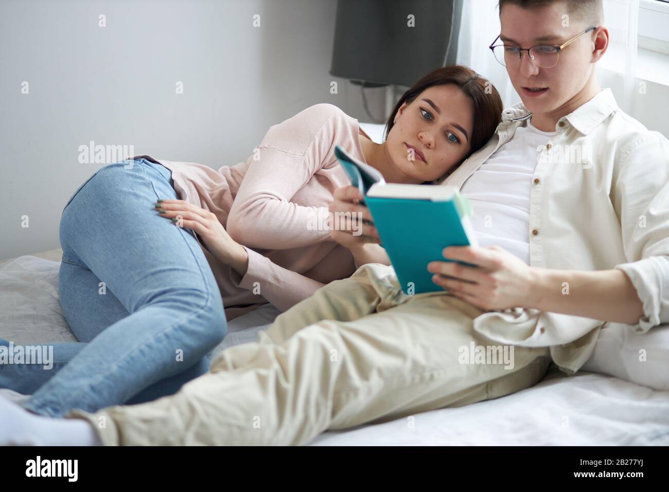 A young handsome clever man is reading a book to his wife ,close up side view photo, education, bookworms. free time, spare time, lifestyle Stock Photo