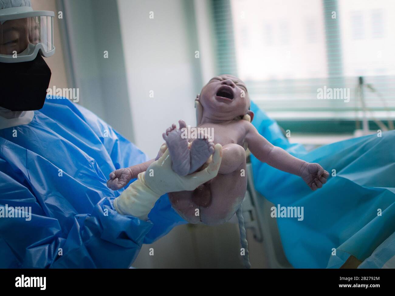 Midwife Wu Dan takes the newborn to the mother Liu Ting at the delivery room of Wuhan Maternal and Child Health Hospital in Wuhan, central China's Hubei Province, March 1, 2020. In the early morning of Feb. 29, volunteer Wang Zhen drove out of his community immediately after receiving a call for help from a pregnant woman who lived 30 kilometers away at another community in Wuhan. Wang took the pregnant woman and her family to the Wuhan Maternal and Child Health Hospital, where the woman later safely gave birth to her baby. On Jan. 23, Wang Zhen, a Stock Photo