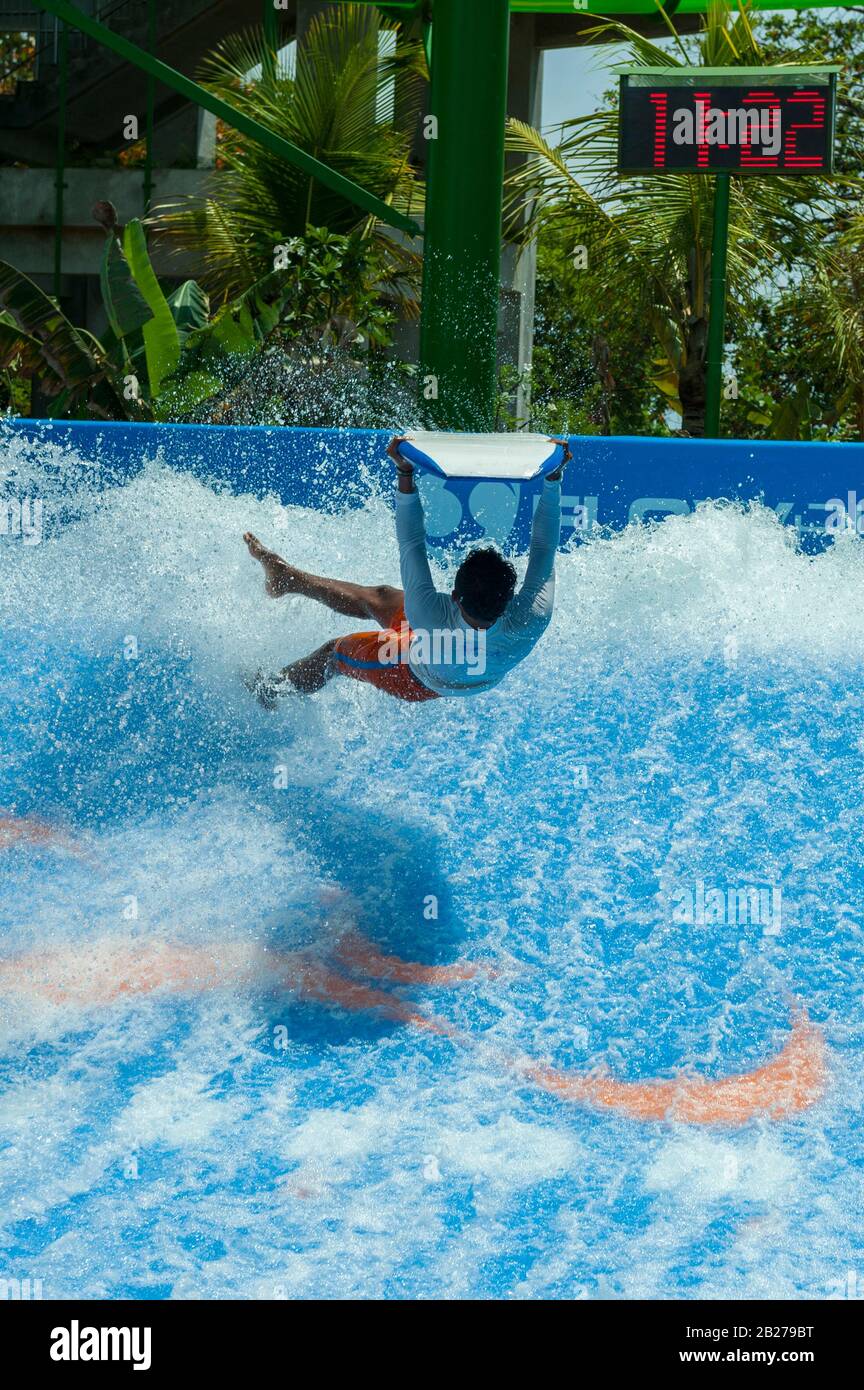 young man performing tricks on boogie-board (body board) on artificial wave. Kuta, Bali, Indonesia Stock Photo