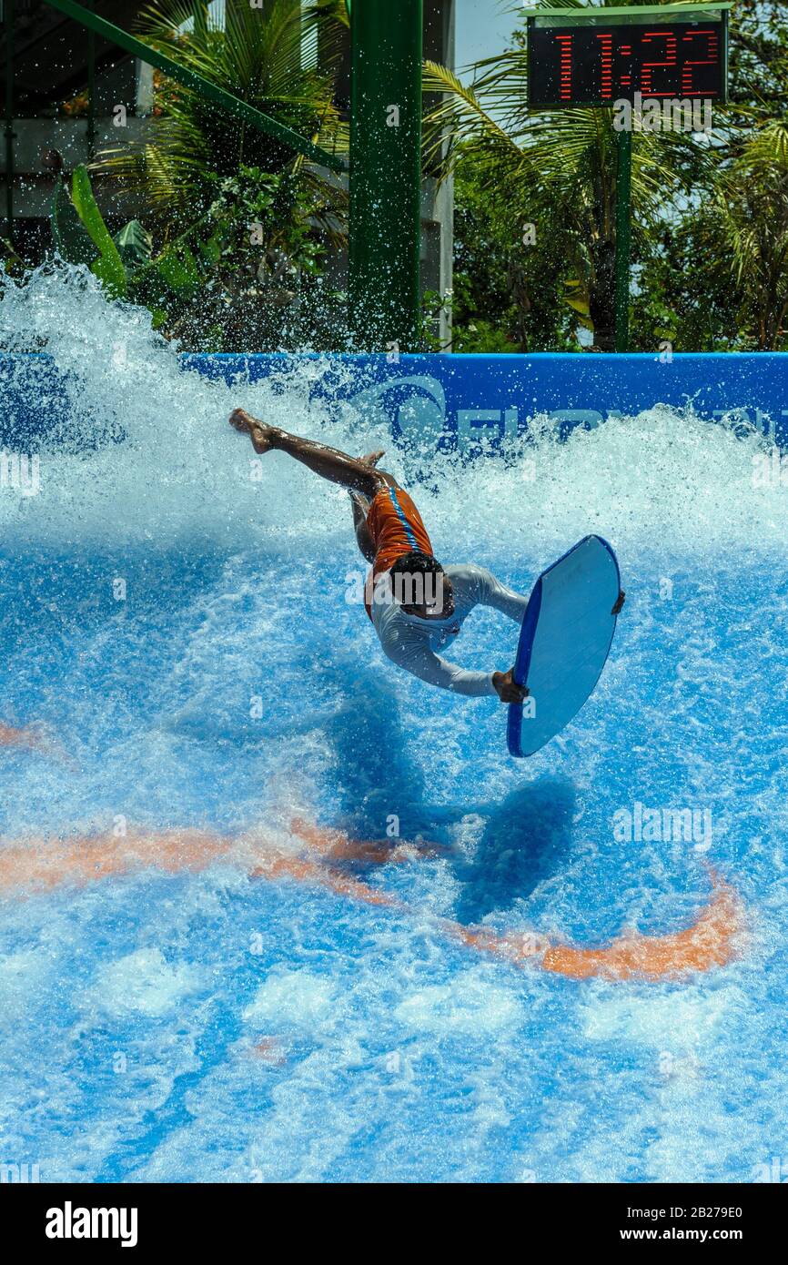 young man performing tricks on boogie-board (body board) on artificial wave. Kuta, Bali, Indonesia Stock Photo