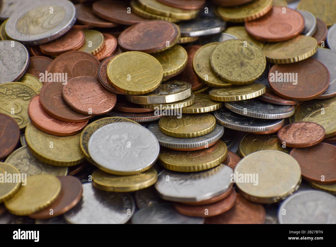 A close up of pile of coins comprised of multiple currencies. Euro