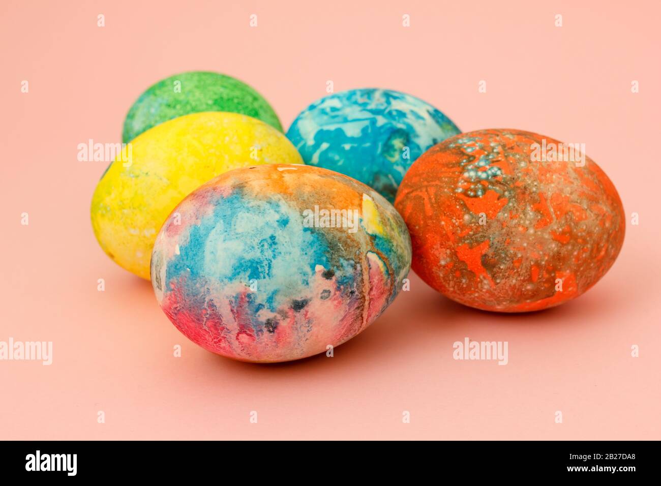 Four multi-colored Easter eggs on pink background top view, space for text. Concept happy easter day. Stock Photo