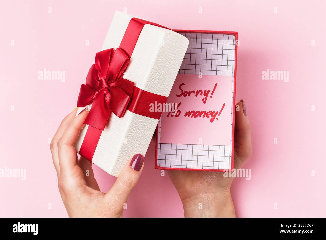 Girl opens a box with a gift on a pink background, top view. Concept no money for gifts Stock Photo