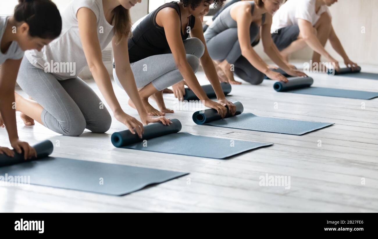 Multiethnic people folding mats finished yoga session at sport club Stock Photo