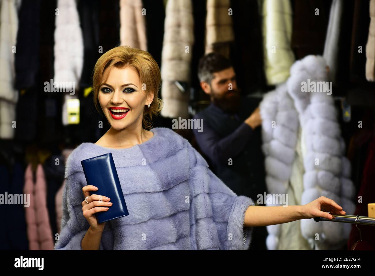 Lady tries expensive mink overcoats on. Man and girl with happy faces