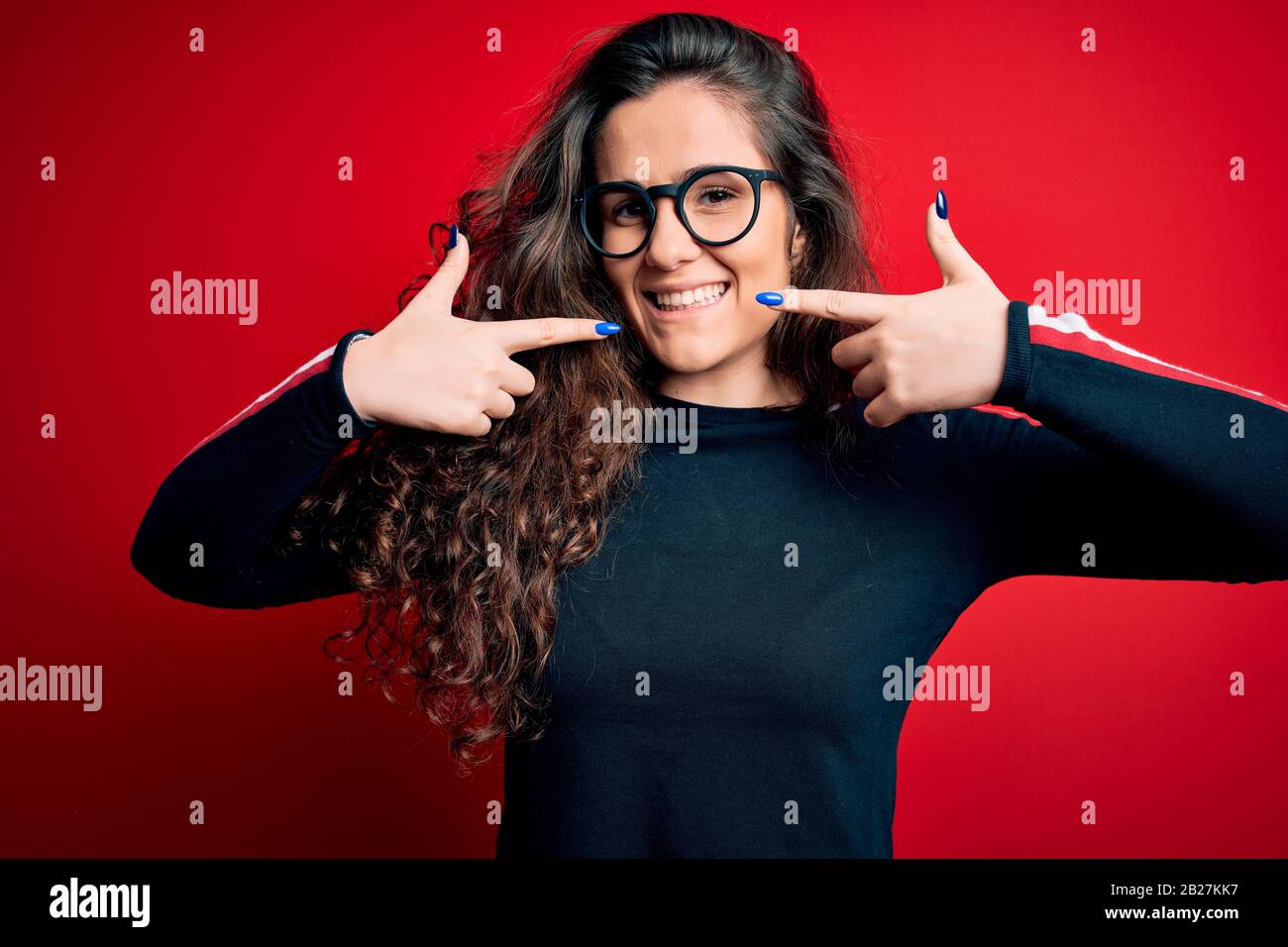 Young beautiful woman with curly hair wearing sweater and glasses over ...