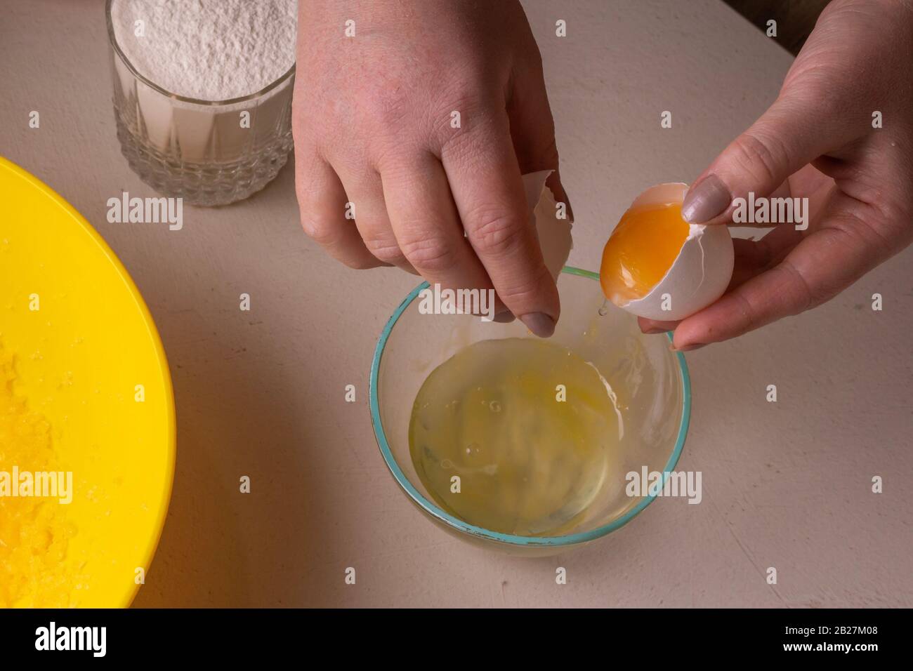 A woman breaks an egg into a glass dish to make a pie Stock Photo Alamy