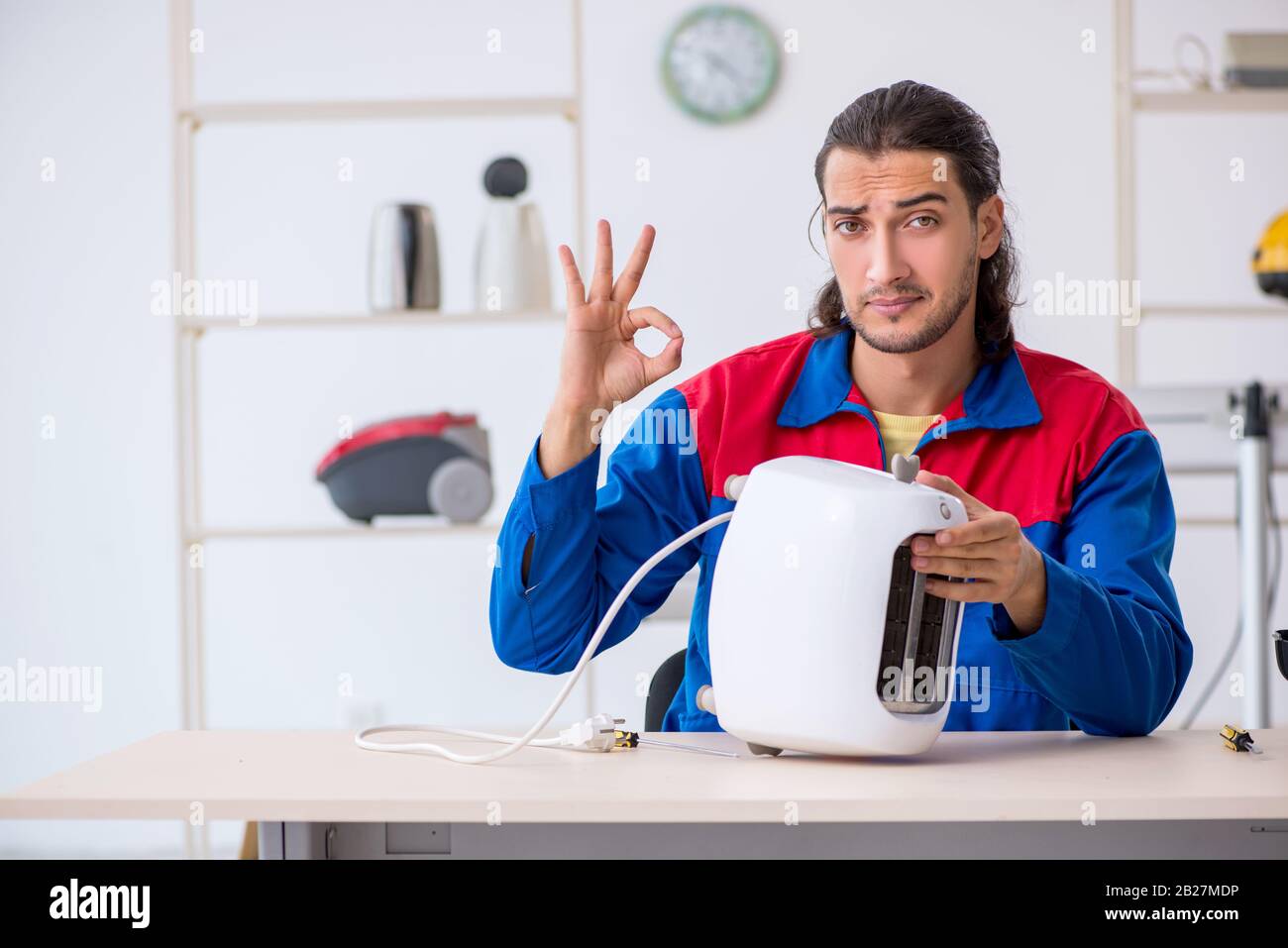 The young male contractor repairing toaster at workshop Stock Photo