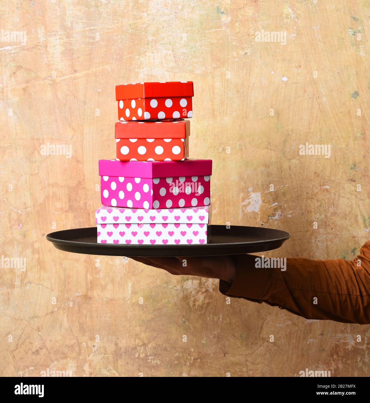 Waiter Box Waiter with pink and red presents on tray. Male hand holds boxes on ...