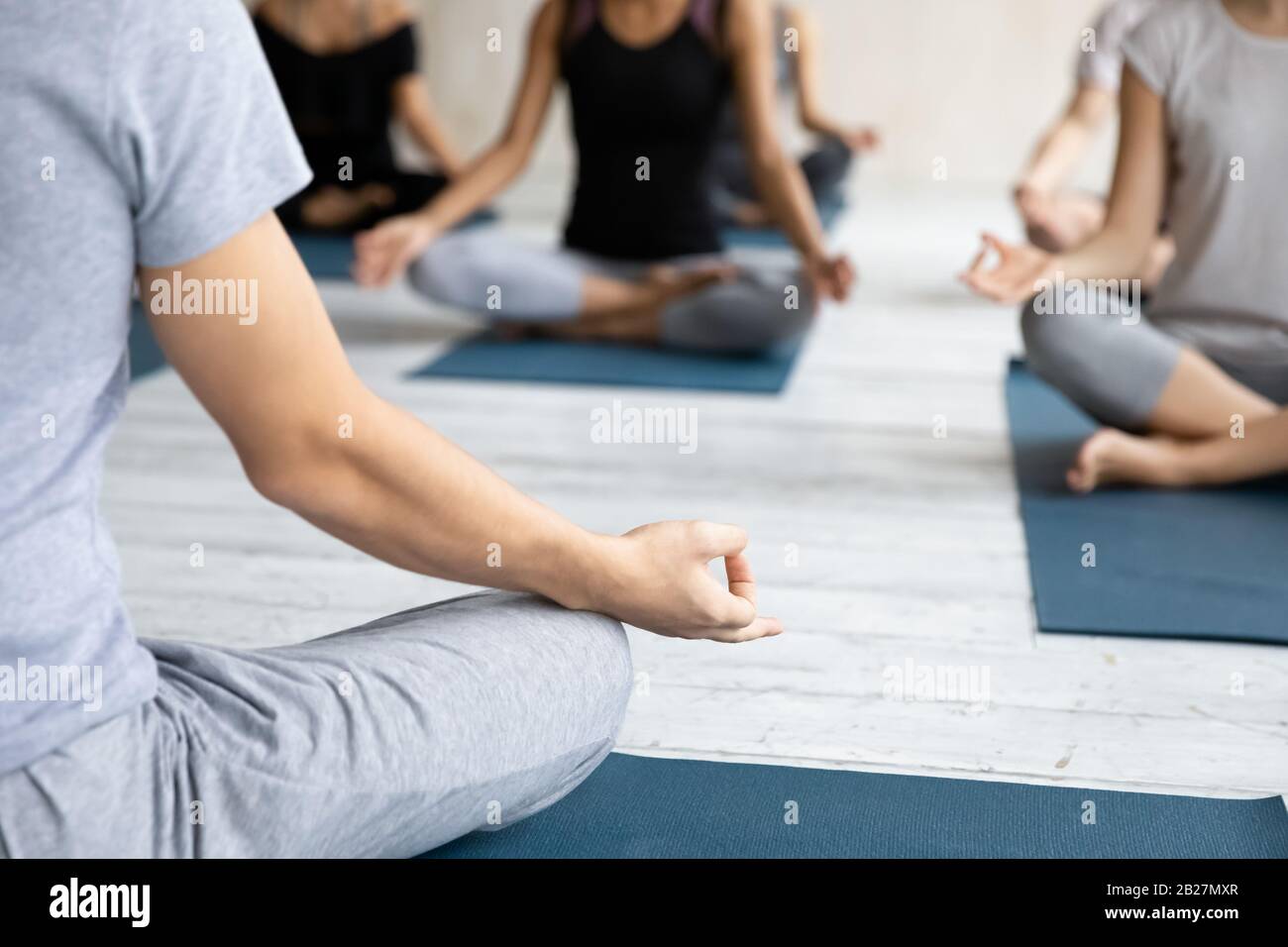 Yogi coach and group of people meditating during yoga class Stock Photo