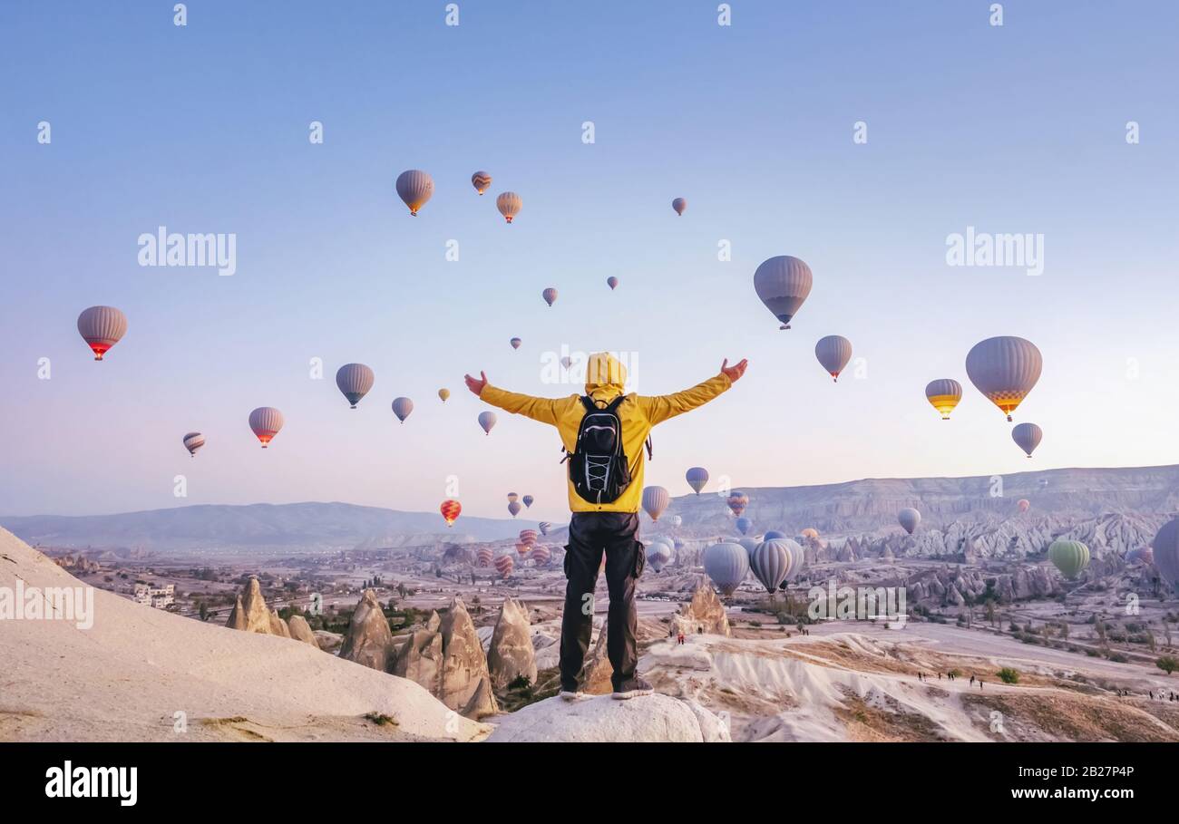 At dawn a tourist with a backpack on the background of soaring hot air balloons in Cappadocia, Turkey Stock Photo