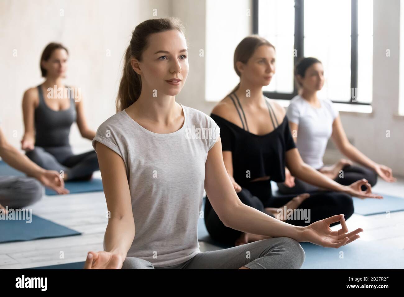 Female yoga instructor and like-minded group of people meditating Stock Photo
