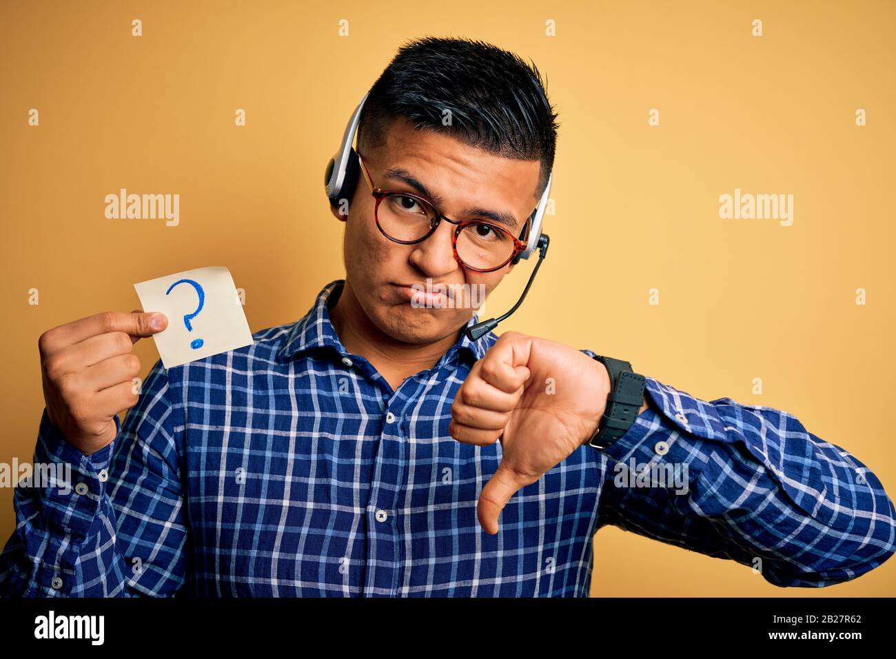 Young latin call center agent man holding question mark reminder paper ...