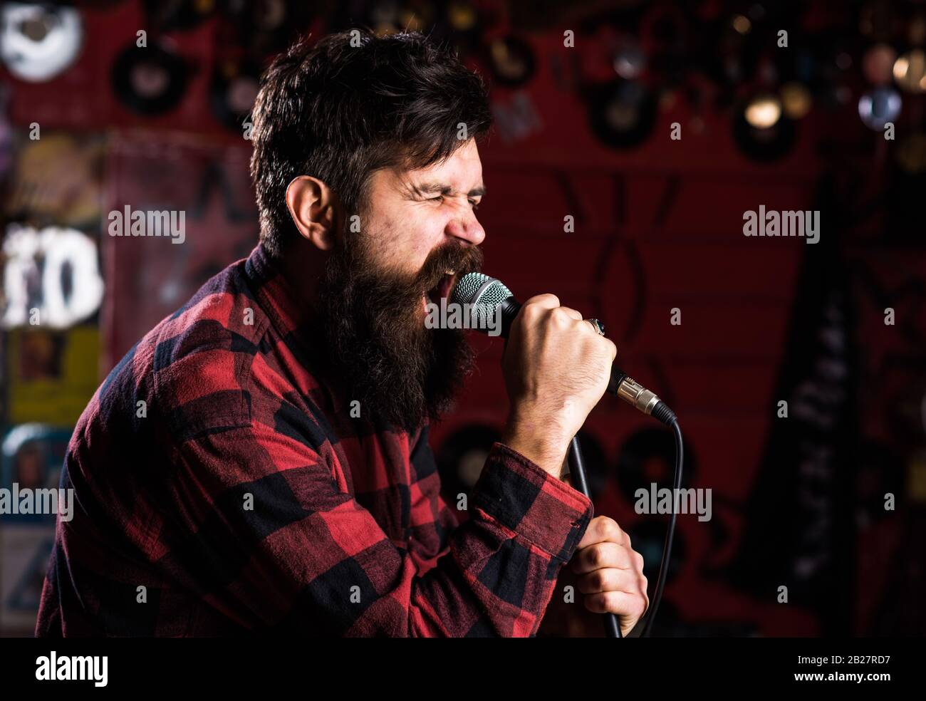 Brutal bearded singer with microphone on stage. Rock star concept. Guy ...