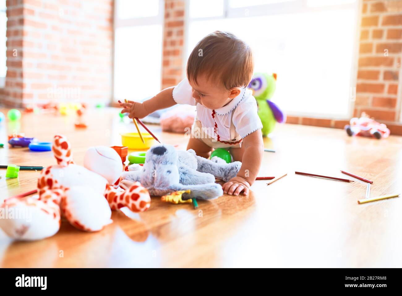Adorable toddler crawling around lots of toys at kindergarten Stock ...