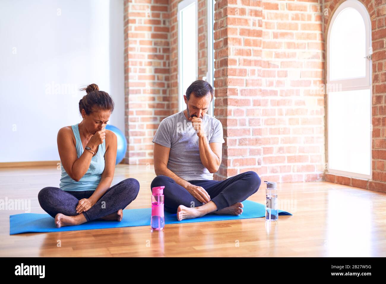 Middle age sporty couple sitting on mat doing stretching yoga Middle age sporty couple sitting on mat doing stretching yoga