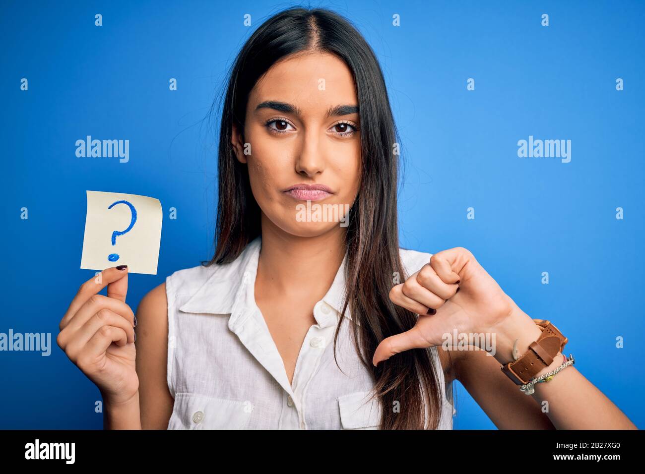 Young beautiful brunette woman holding paper with question mark symbol ...
