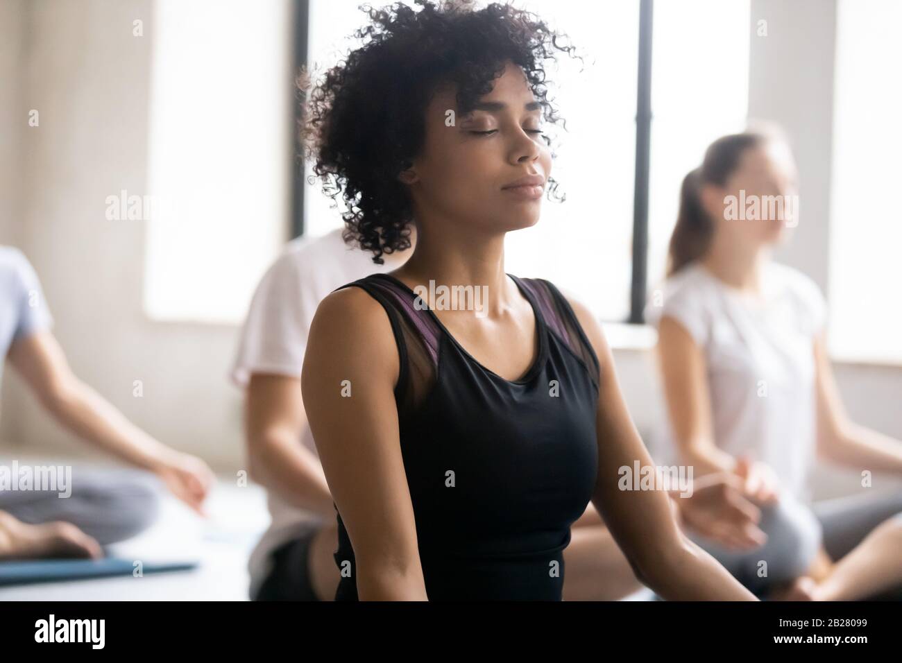 African female closed eyes do meditation practice with associates Stock Photo