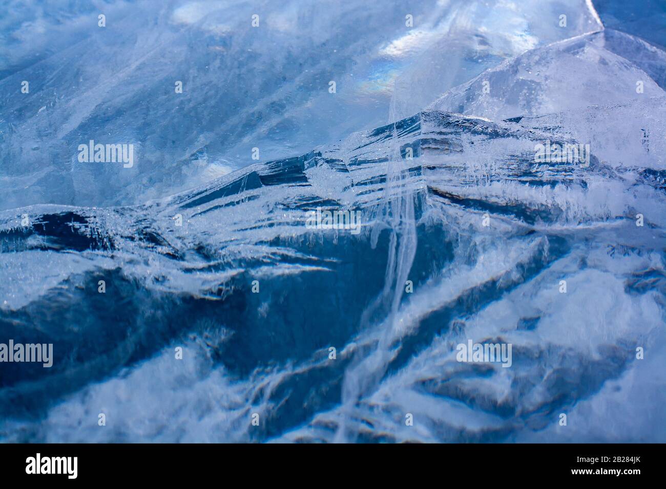 Ice with cracks similar to a mountain landscape. Beautiful ice of blue color. Horizontal. Stock Photo