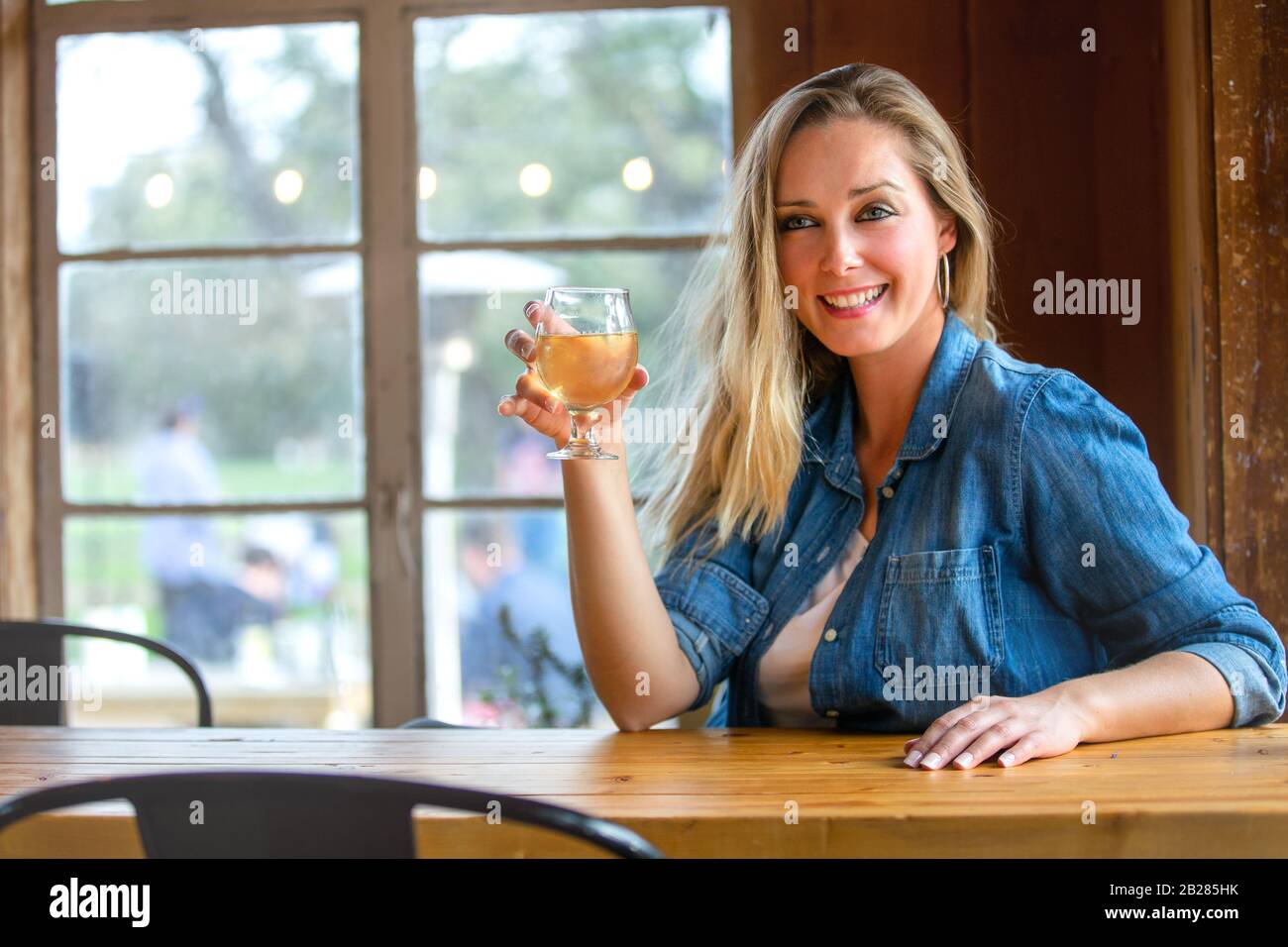 Portrait of a woman in a taproom drinking tap draft pints of craft beer or cider, wine Stock Photo