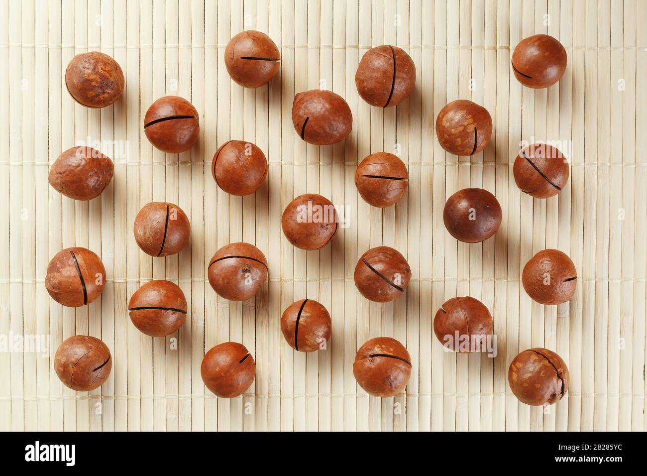 Flat composition with Australian macadamia nuts on bamboo light background. Patterns, repetitions Stock Photo