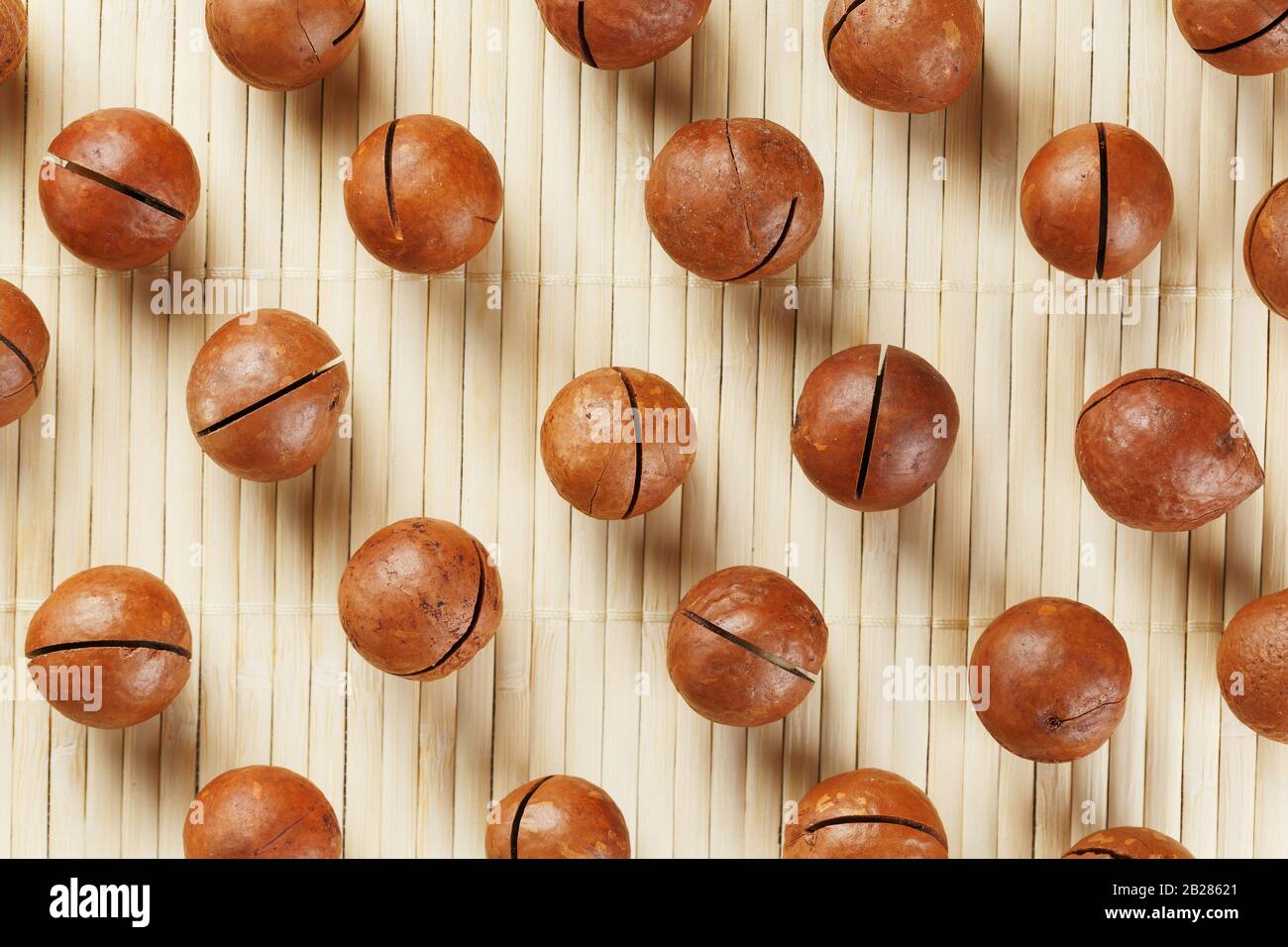 Flat composition with Australian macadamia nuts on bamboo light background. Patterns, repetitions Stock Photo