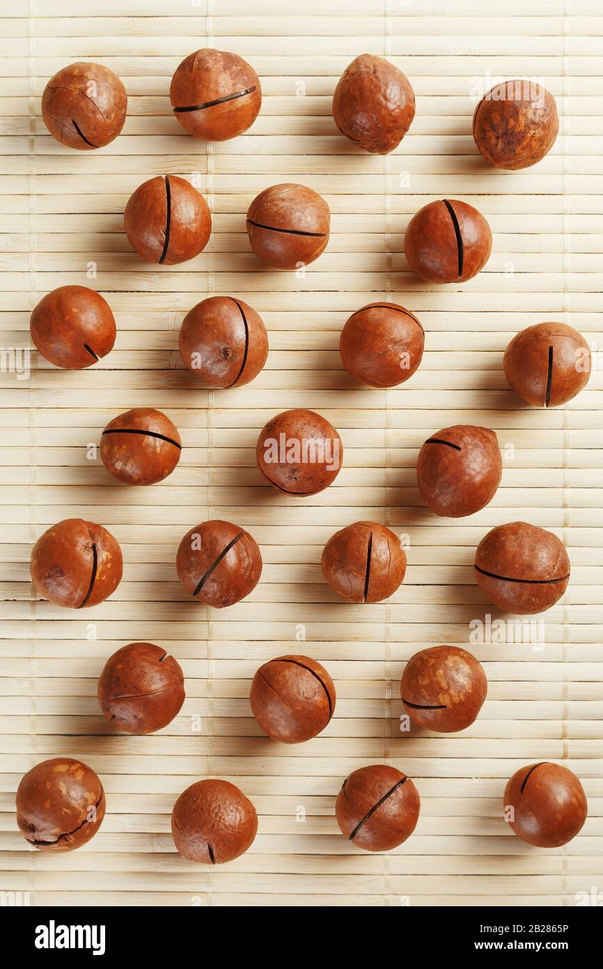 Flat composition with Australian macadamia nuts on bamboo light background. Patterns, repetitions Stock Photo