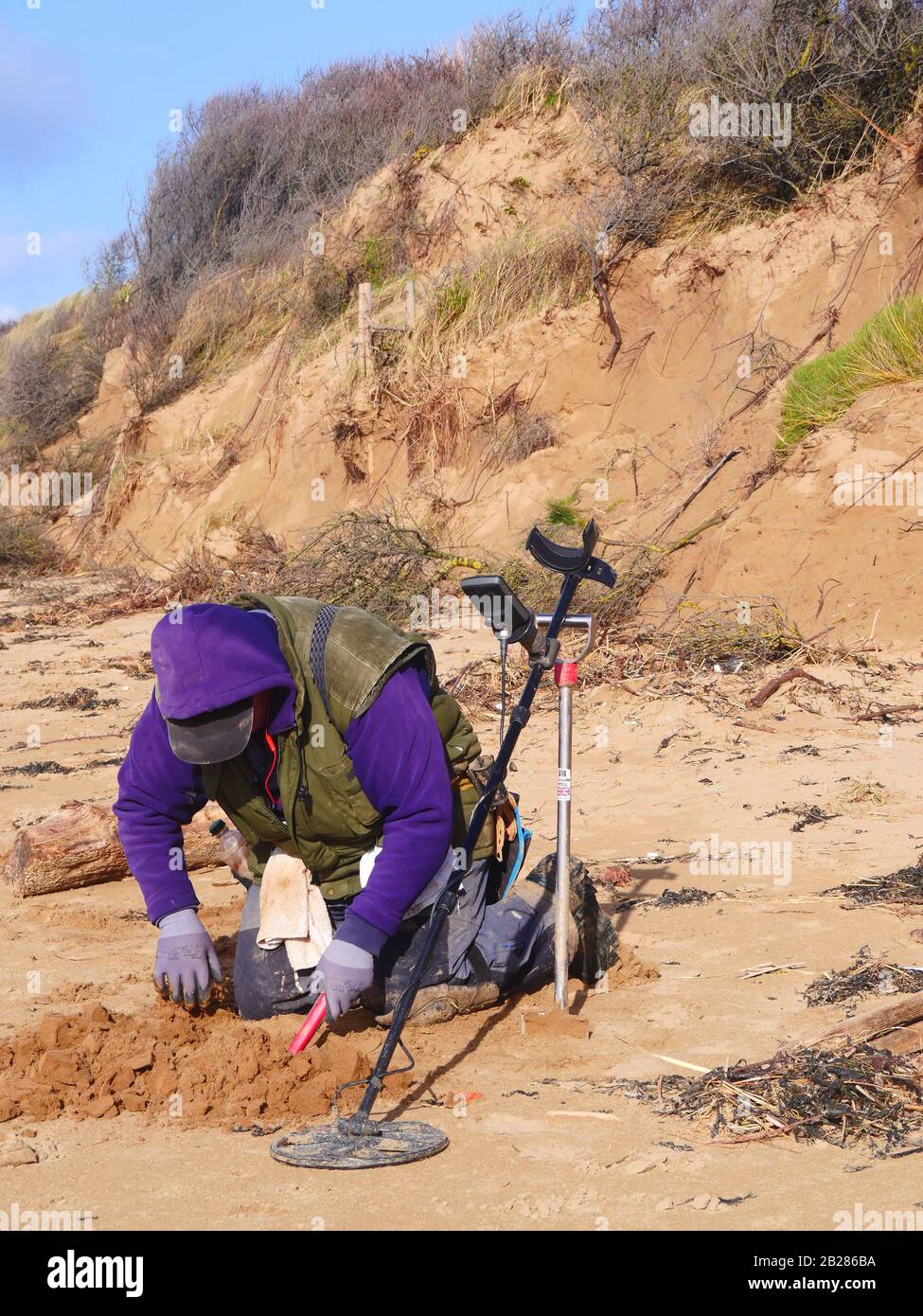 Metal detecting on Somerset beach, UK, man looking in sand for metal