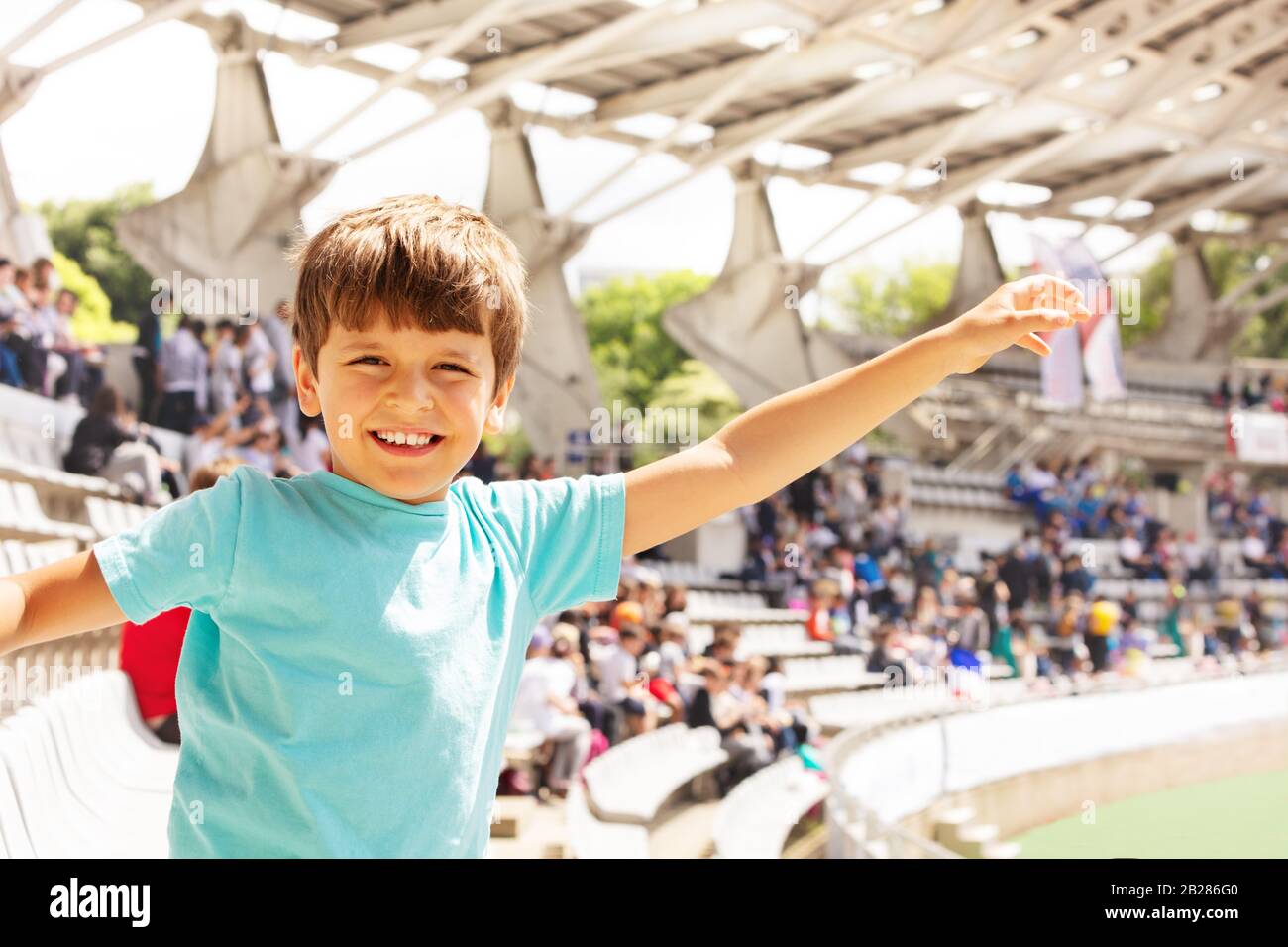 Happy smiling boy on the stadium waving hands smile and look at camera watching sport game Stock Photo