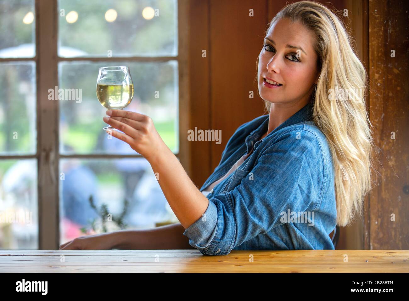 Pretty woman holding up a pint of craft cider or beer in a tulip glass at local brewery Stock Photo