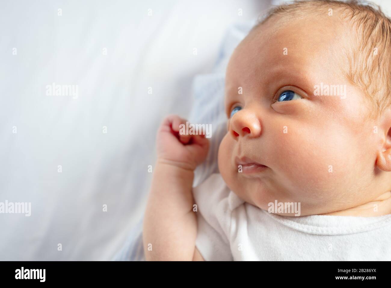 Closeup portrait of the little baby boy calm face laying in the crib