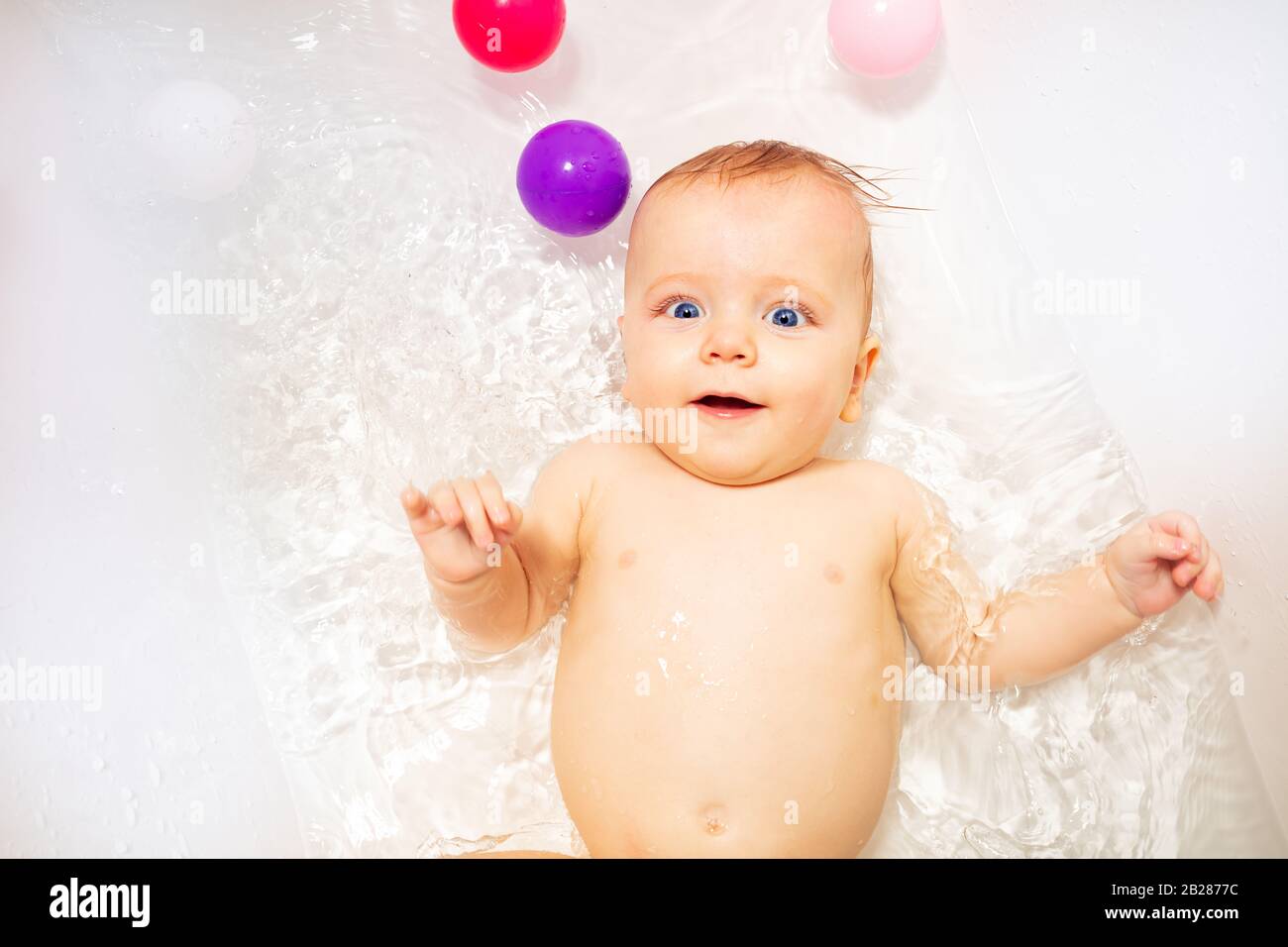 Baby in bath tub bathroom swim in water happy smiling laying on back