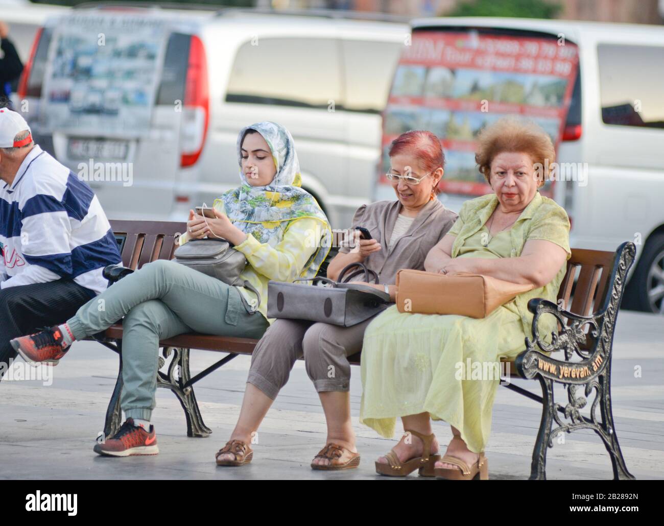 A muslim young women sitting beside two armenian senior ladies in Republic Square, Yerevan, Armenia Stock Photo