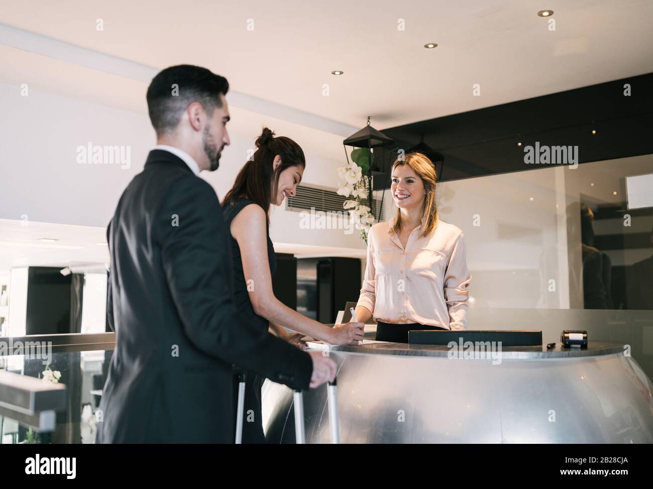 Portrait Of Two Young Business People Check In At Hotel Reception