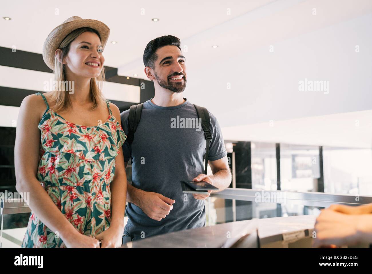 Portrait of lovely couple doing check-in at hotel reception front desk ...
