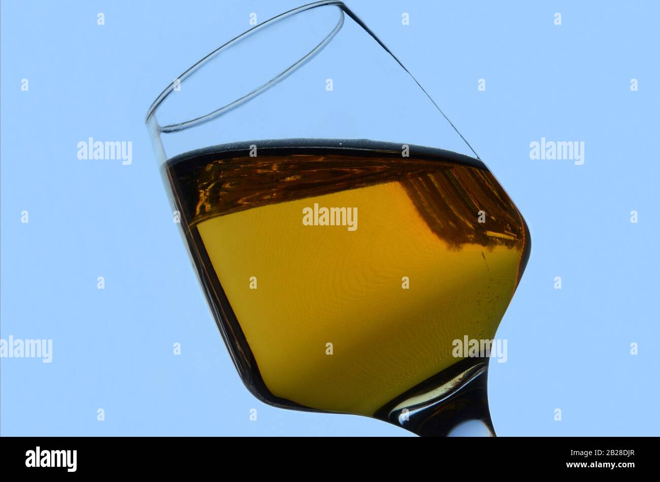 PENDULUM: A glass of beer undergoes an unusual gravitational transformation against a blue backdrop. Stock Photo