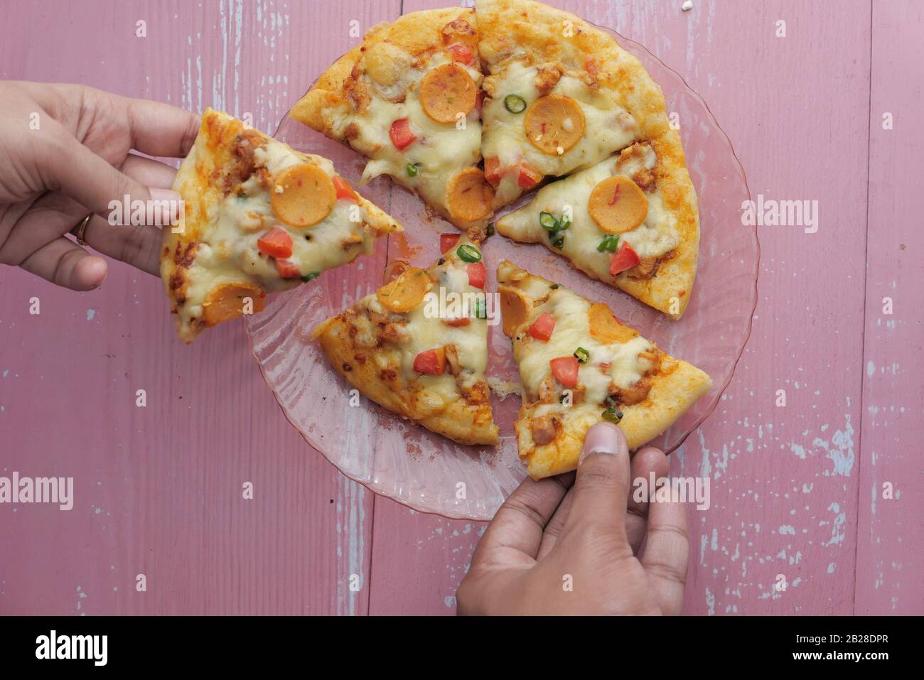 Hands taking pizza slices from plate, top view Stock Photo