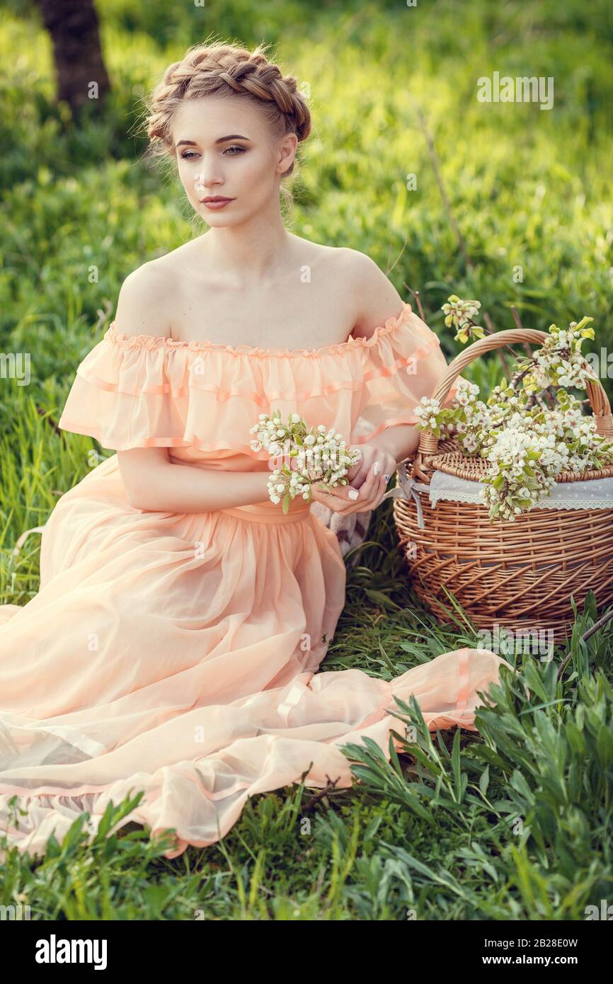 Beautiful young girl in an old dress in a pear-blossoming garden. Beautiful themed photography in retro style Stock Photo