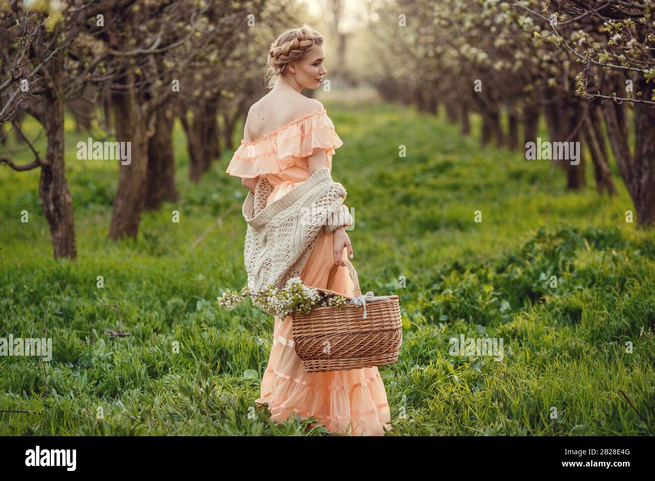 Beautiful young girl in an old dress in a pear-blossoming garden. Beautiful themed photography in retro style Stock Photo