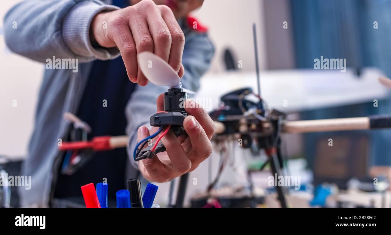Closeup programmer hands making electronic FPV - first person view drone at home office. Developer building constructing DIY quadcopter from kit with Stock Photo