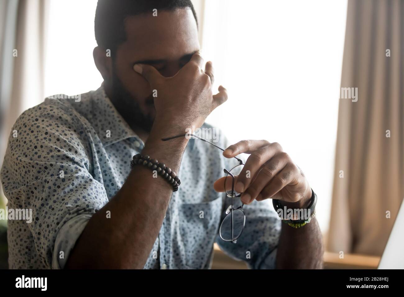Exhausted african ethnicity man having problems with vision. Stock Photo