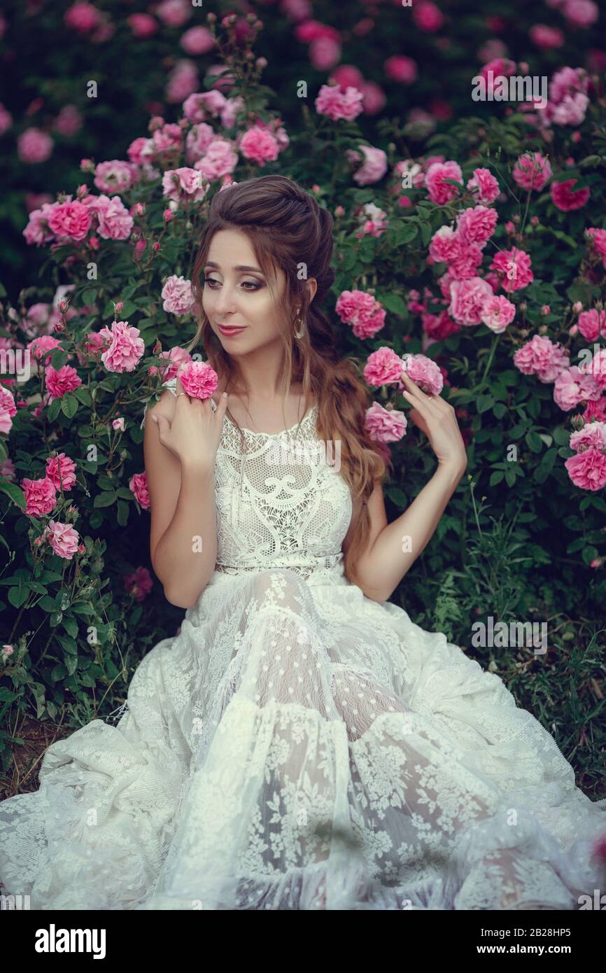 Beautiful Woman In A Floral Park Garden Roses Makeup Hair A Wreath Of Roses Long Wedding Dress Woman In Boho Style Stock Photo Alamy