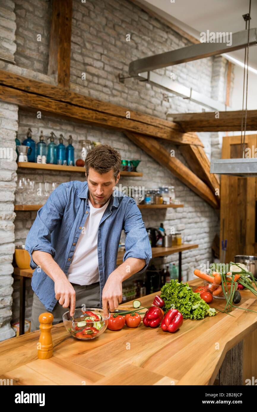 Young man preparing food in the rustic kitchen Stock Photo