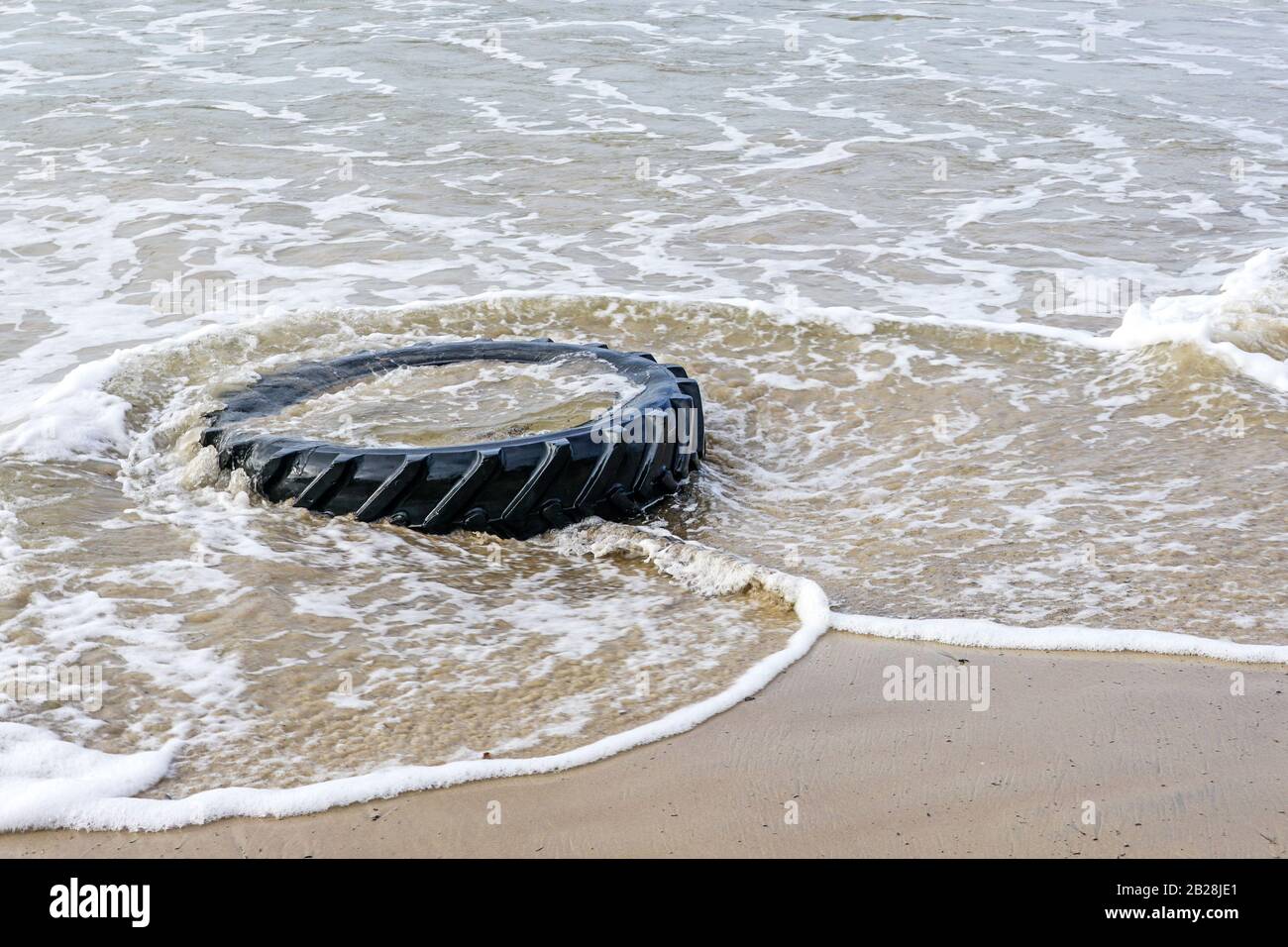 marine pollution by industrial waste, tractor tire in sea water Stock